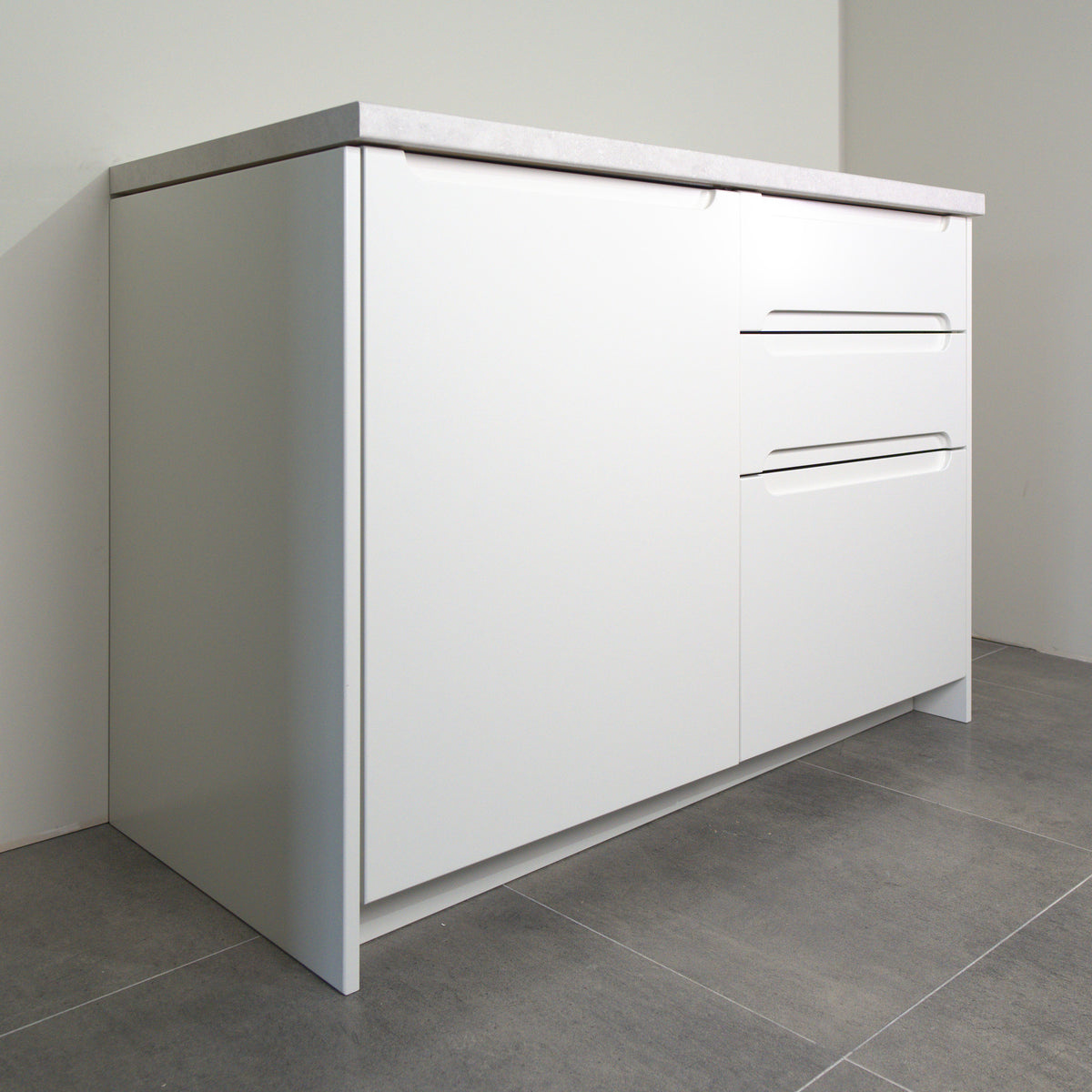 Grip fronts in white lacquer on a kitchen cabinet, angled view from the left