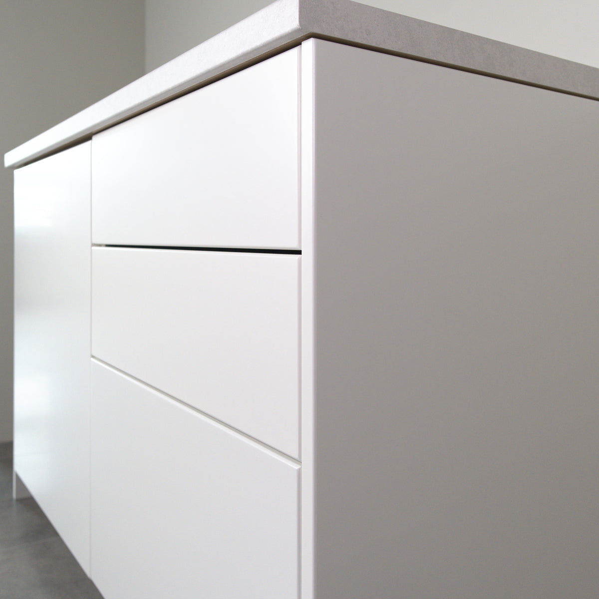 Smooth fronts in white lacquer on a kitchen cabinet, angled view from the right