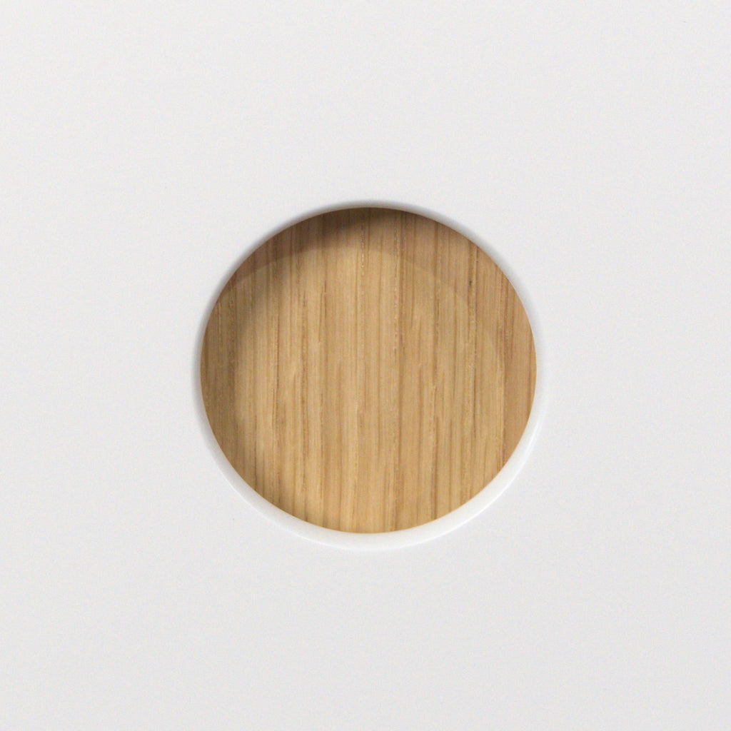 Round 50 mm handle hole lined with oak veneer in a white Round Oak front, close-up