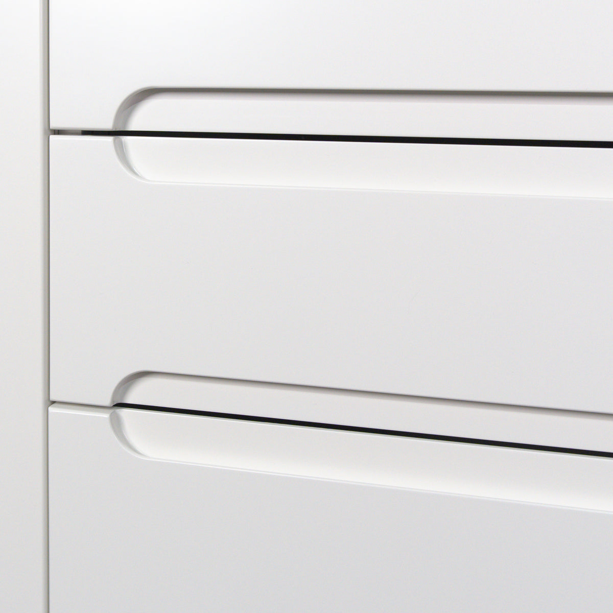 Handle pocket with a rounded end at the top edge of a drawer, Grip front in white lacquer close up